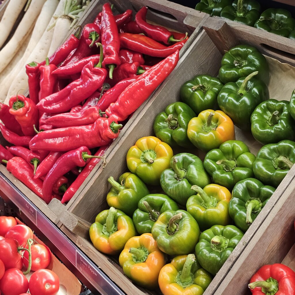 Wooden crates filled with red, green, and yellow bell peppers.