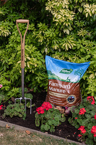 A picture of a garden fork and Westland's Farmyard Manure